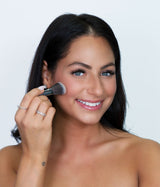 Beauty shot of a beautiful lady using Vasanti Stubby Blush Brush on her cheeks.