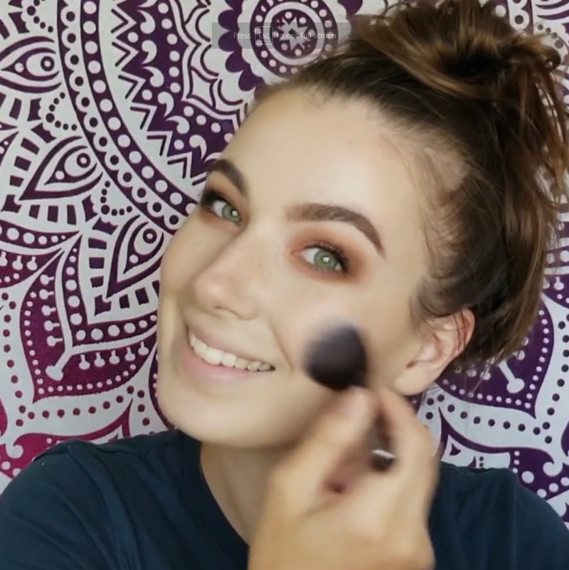 A girl using Vasanti Stubby Blush Brush to apply makeup on her cheeks.