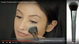 A girl applying powder using Vasanti Powder Finisher - Finish it off Brush - Screenshot from Youtube video