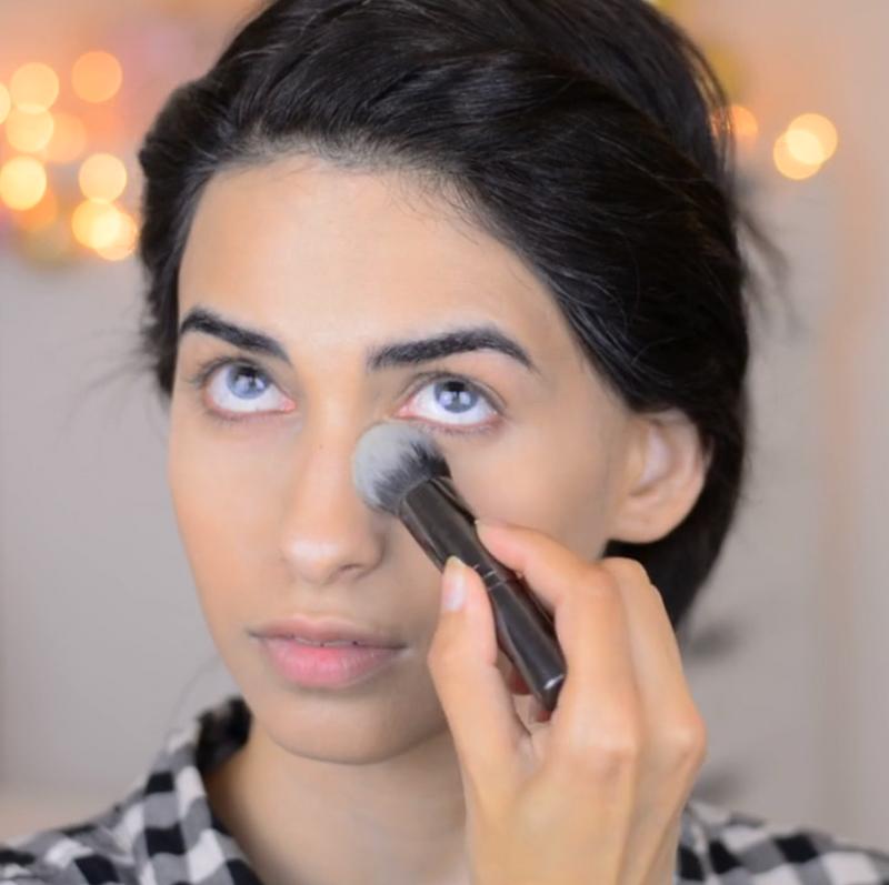 A girl applying makeup on her undereye using Vasanti Stubby Round Foundation Brush.